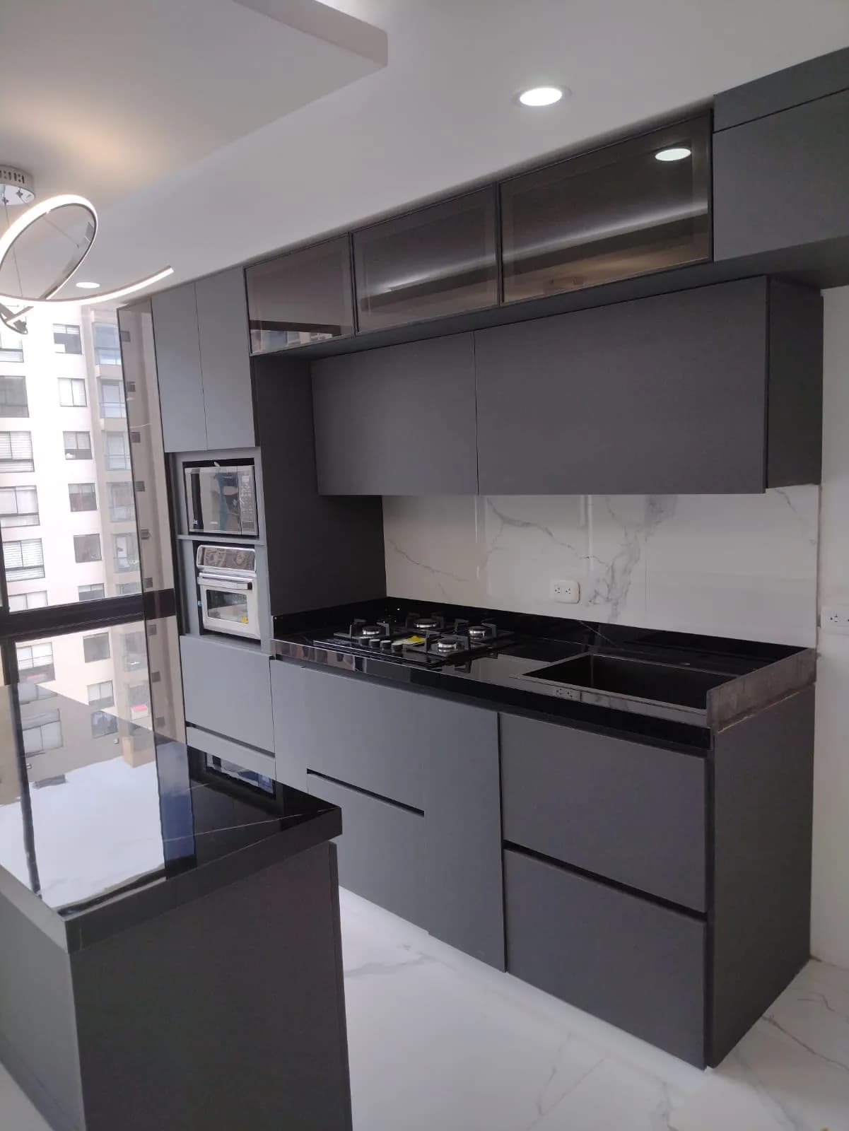 Cocina terminada en grafito, con mesón negro, enchape de mármol y horno empotrado